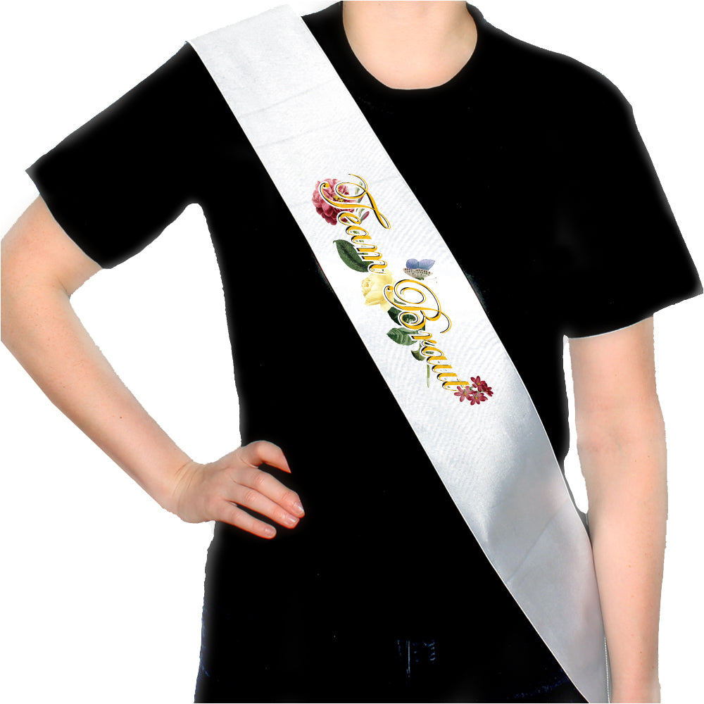 JGA Schärpe "Schnörkel Team" mit buntem Blumen- und Schmetterlingsmotiv sowie goldgelbem Schriftzug "Team Braut", hochwertig durch Sublimationsverfahren bedruckt und glänzend, ideal für das Braut-Team beim Junggesellinnenabschied.
