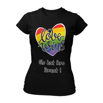 Damen T-Shirt "Love wins! Sie hat Ihre Braut!" im Regenbogen-Look, mit verspieltem Schriftzug „love wins“ auf einem herzförmigen Hintergrund. Das Shirt feiert die gleichgeschlechtliche Ehe und betont mit dem zusätzlichen Slogan „Sie hat ihre Braut!“, dass hier zwei Frauen heiraten. Hergestellt aus hochwertigem Material mit Doppelnähten, ist es ein ideales, figurbetontes JGA-Shirt für einen bunten und offenen Junggesellinnenabschied.