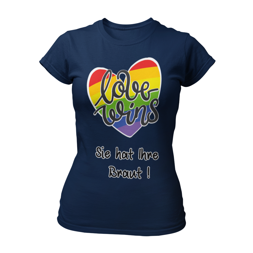 Damen T-Shirt "Love wins! Sie hat Ihre Braut!" im Regenbogen-Look, mit verspieltem Schriftzug „love wins“ auf einem herzförmigen Hintergrund. Das Shirt feiert die gleichgeschlechtliche Ehe und betont mit dem zusätzlichen Slogan „Sie hat ihre Braut!“, dass hier zwei Frauen heiraten. Hergestellt aus hochwertigem Material mit Doppelnähten, ist es ein ideales, figurbetontes JGA-Shirt für einen bunten und offenen Junggesellinnenabschied.