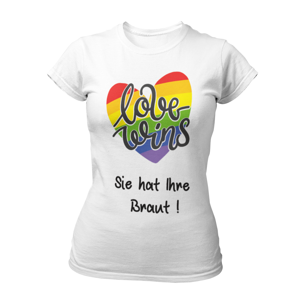 Damen T-Shirt "Love wins! Sie hat Ihre Braut!" im Regenbogen-Look, mit verspieltem Schriftzug „love wins“ auf einem herzförmigen Hintergrund. Das Shirt feiert die gleichgeschlechtliche Ehe und betont mit dem zusätzlichen Slogan „Sie hat ihre Braut!“, dass hier zwei Frauen heiraten. Hergestellt aus hochwertigem Material mit Doppelnähten, ist es ein ideales, figurbetontes JGA-Shirt für einen bunten und offenen Junggesellinnenabschied.