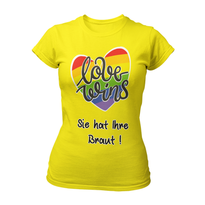 Damen T-Shirt "Love wins! Sie hat Ihre Braut!" im Regenbogen-Look, mit verspieltem Schriftzug „love wins“ auf einem herzförmigen Hintergrund. Das Shirt feiert die gleichgeschlechtliche Ehe und betont mit dem zusätzlichen Slogan „Sie hat ihre Braut!“, dass hier zwei Frauen heiraten. Hergestellt aus hochwertigem Material mit Doppelnähten, ist es ein ideales, figurbetontes JGA-Shirt für einen bunten und offenen Junggesellinnenabschied.