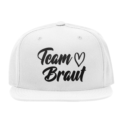 JGA Cap „Team Braut – Herzen“ mit flachem Schirm und vier gestickten Ösen. Die Kappe ist mit einer „Team Braut“ Aufschrift und Herzmotiven auf der Vorderseite bedruckt. Der PVC-Verschluss auf der Rückseite ist größenverstellbar, was eine individuelle Anpassung ermöglicht. Diese Premium JGA-Kappe ist das perfekte Accessoire für die Begleiterinnen der Braut.