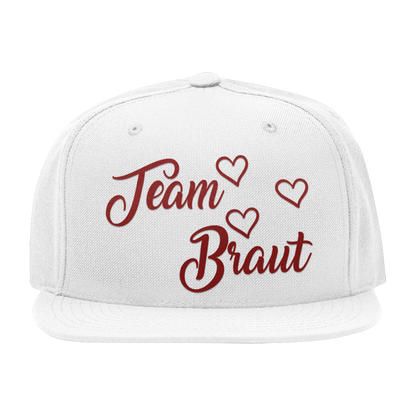 JGA Cap „Team Braut“ mit flachem Schirm und roten „Team Braut“ Schriftzug sowie Herzen auf der Vorderseite. Die Kappe hat vier gestickte Ösen für Belüftung und einen größenverstellbaren PVC-Verschluss auf der Rückseite.